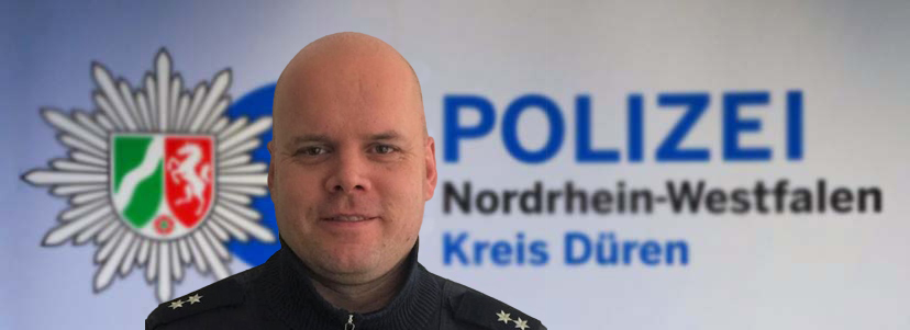 Michael Bich vor Leinwand mit Logo der Kreispolizeibehörde Düren 