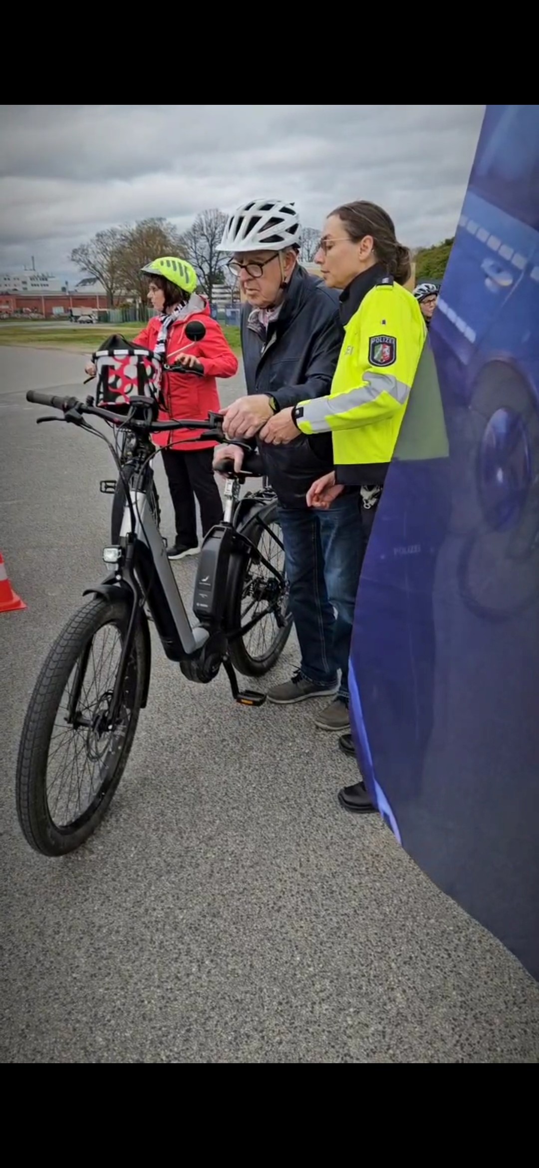 Eine Polizistin erklärt einem älteren Mann etwas an seinem Pedelec. 