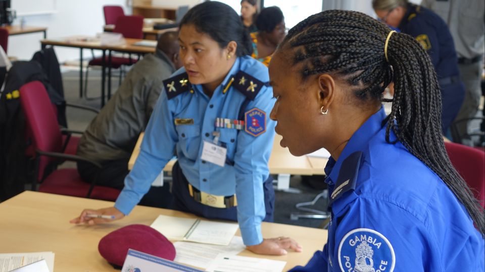 Two seminar participants stand at a table and discuss.